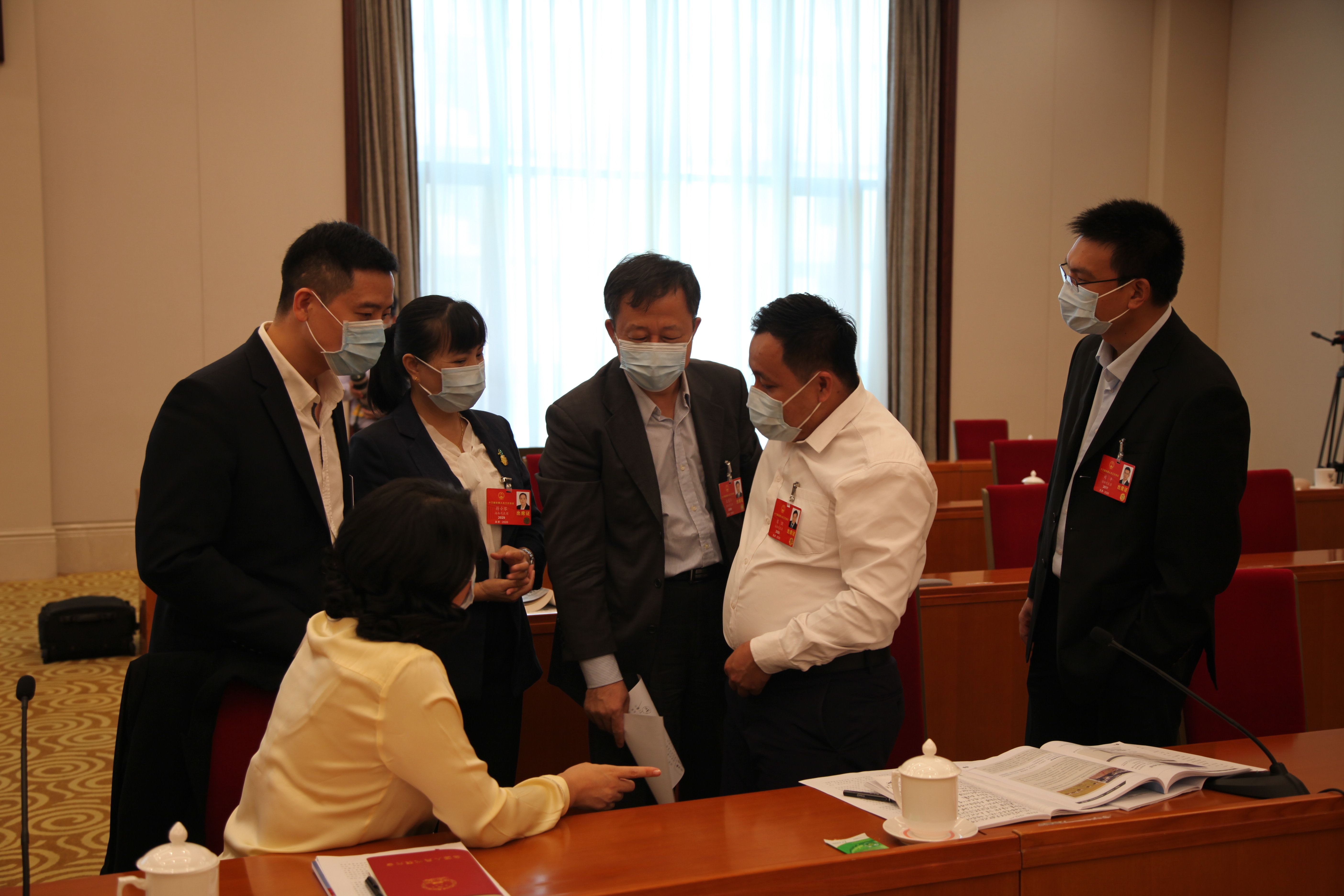 5月24日，海南代表团审查计划报告和预算报告，图为会议间隙，代表们相互交流讨论。张旭图